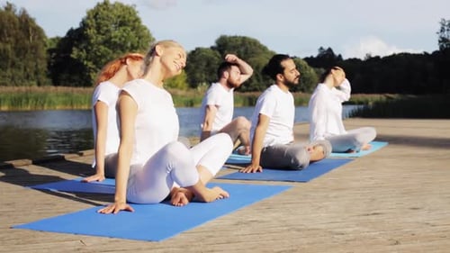 Group meditation in lotus pose on a river berth for fitness and wellness
