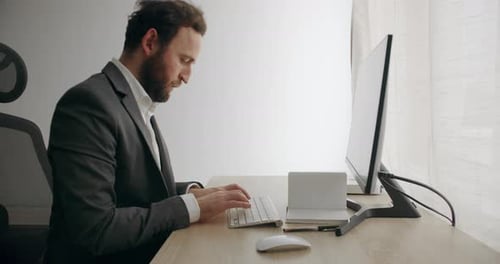 Man Typing at Computer in Bright Office