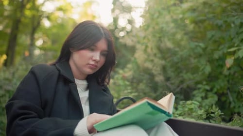Calm Woman Reading on Park Bench Adjusting Hair in Autumn