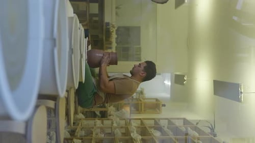 VERTICAL male potter shaping clay spinning on pottery wheel in studio small business workshop