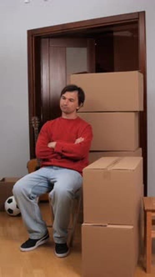 Man Sitting Next to Moving Boxes Indoors