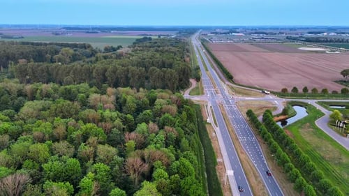 Moderne Autobahn entlang des landwirtschaftlichen Feldes und des tiefen Waldes.