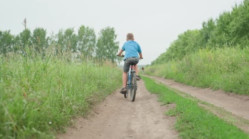 Boy Rides a Bike on a Country Road