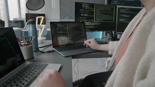 Female Programmer Codding on Different Computers in Office