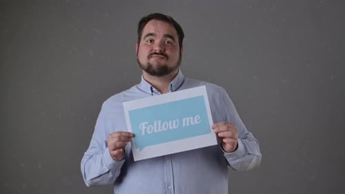 Homem segurando a placa Siga-me em fundo cinza