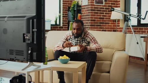 Man Eats Noodles, Watches TV at Home