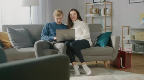 Couple Relaxing on Couch Looking at Laptop