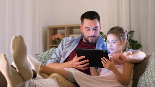 Father and Daughter Relaxing Using Tablet at Home
