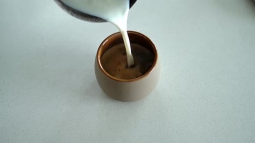 Milk being poured into coffee close up