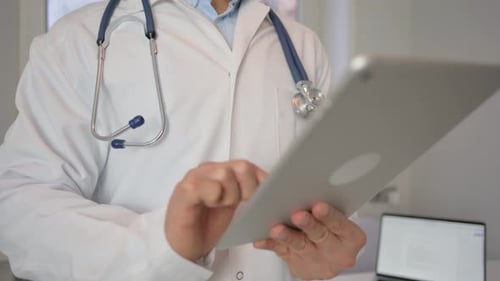 Busy Doctor Typing on Digital Tablet