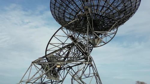 Rotating Radio Telescope Against Cloudy Blue Sky