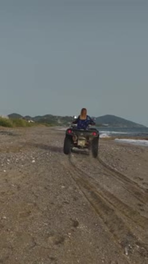 Vertical Video Beautiful Model Riding a Quad Bike Along the Waves of the Mediterranean at Sunset