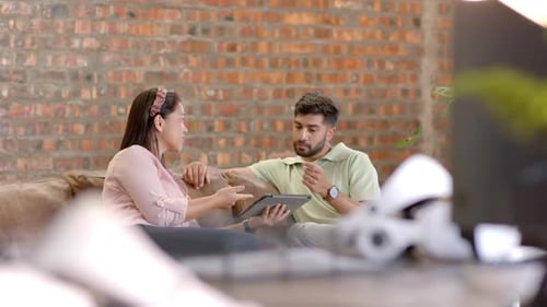Discuter des détails du projet, collègues utilisant une tablette assis sur le canapé du bureau