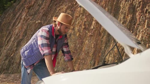 Nervous Caucasian Young Bearded Man Looking Sadly on Car Engine Breakdown Thinking and Waiting for