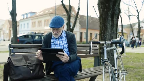 Senior Man with Tablet on Park Bench