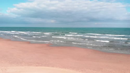 Turquoise sea waves gently rolling onto golden sandy beach