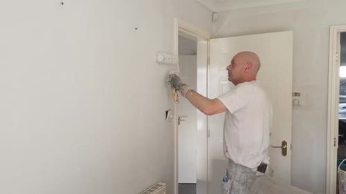 Decorator applies fresh paint to living room wall.
