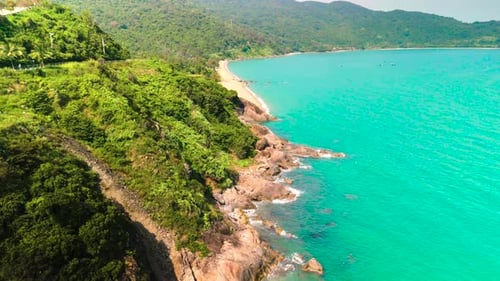 Aerial View of a Stunning Tropical Coastline Where Turquoise Ocean Waves Meet a Rocky Shore Adorned