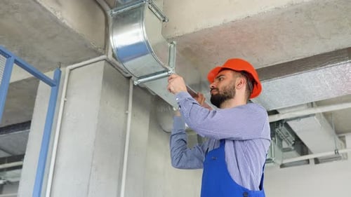 Man Working on Air Conditioning Ducts in Building