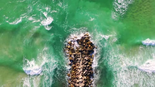 Aerial View of Waves Crashing on Breakwater