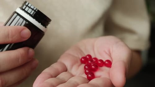 Hand Holding Vitamin E Pills