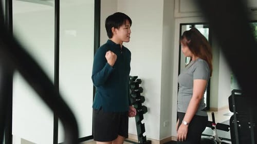 Personal Trainer Motivating Female Client During Gym Workout Session