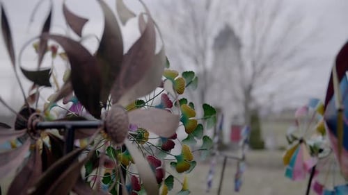 A rainbow of colourful pinwheels spinning in front of a church.