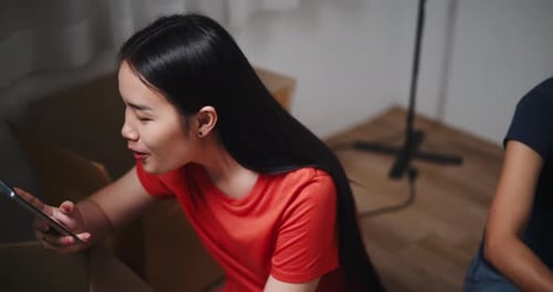Young Woman Video Chatting While Unpacking Boxes