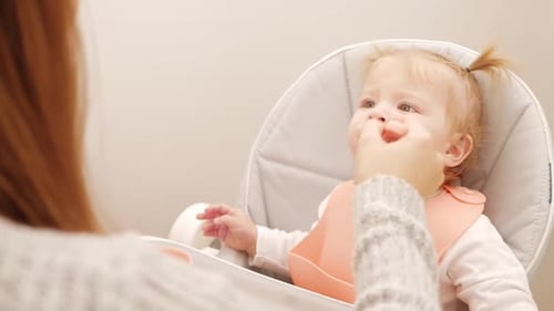 Baby Being Fed in Highchair Indoors
