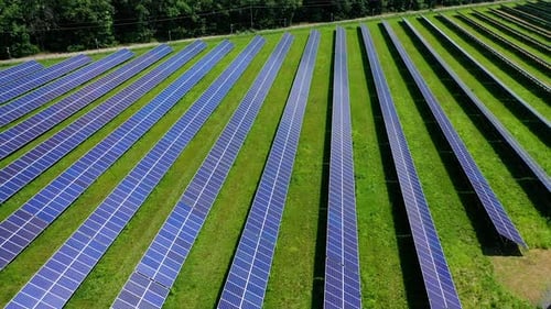 Rows of solar panels on green field.