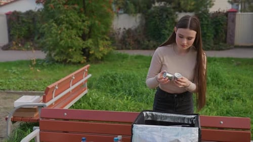 Mujer joven arreglando artículos de una bolsa de entrega en el parque Mujer individual organizando sus compras en