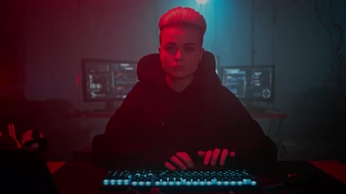 Young Adult Typing on Glowing Keyboard in Dark Room