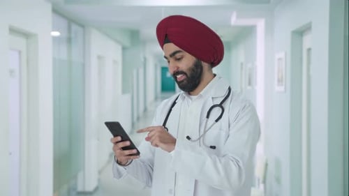 Young Doctor Using Smartphone in Hospital Hallway
