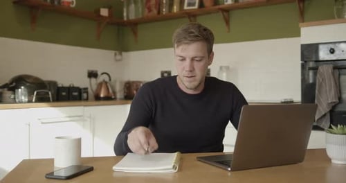 Man Works at Laptop in Sunny Kitchen