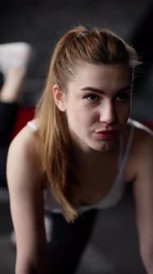 Focused Young Woman in Activewear Resting Between Workouts in a Gym Determination in Her Eyes
