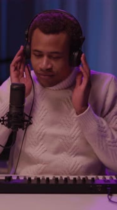 A Musician in a Studio Plays Keyboard and Sings Showcasing His Artistry