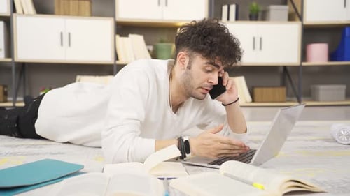 Young Man Using Laptop and Talking on Phone
