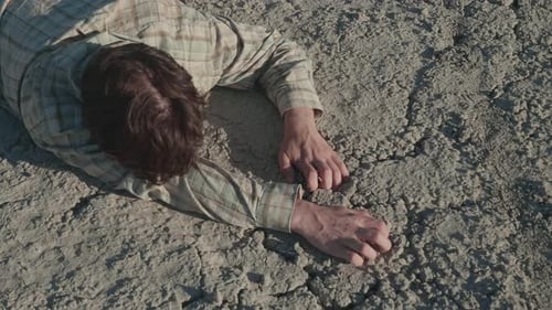 Man Lies on Dry, Cracked Earth in Desert