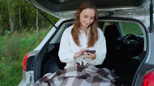Young Woman Uses Smartphone in Back of Car
