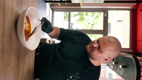 Vertical Video Close Up in a Fast Food Establishment Large Chef in a Black Uniform Prepares Japanese