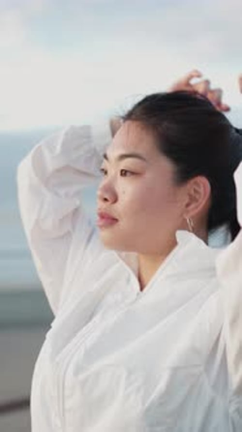 Woman Ties Up Hair Before Outdoor Exercise