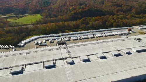 Top View of Giant Logistics Center with Many Commercial Trailer Trucks Unloading and Uploading