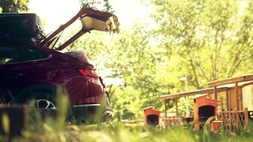 A Red Car with Open Trunk in Green Camping
