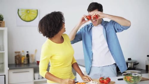 Playful couple preparing food together in home kitchen