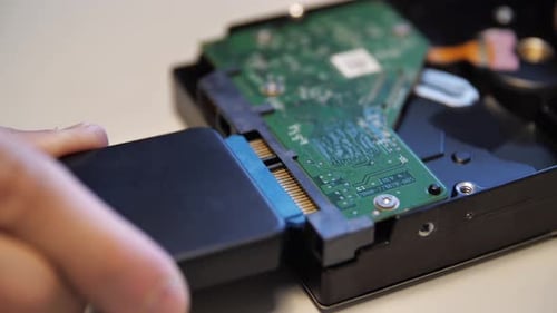 Techniker verbindet Festplatte mit Adapter auf weißem Hintergrund