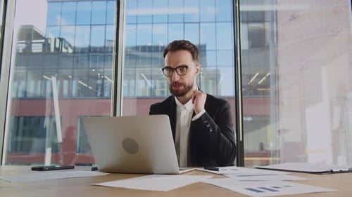 Man Attends Virtual Meeting at Desk in Modern Office