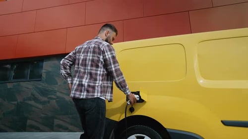 Man Unplugs Charging Cable from Electric Vehicle