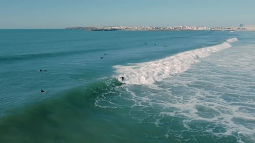 Beautiful aerial view of a surfer riding a perfect wave in the blue sea. He is making cool tricks.