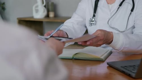 Doctor Reviews Medical Records with Patient at Desk