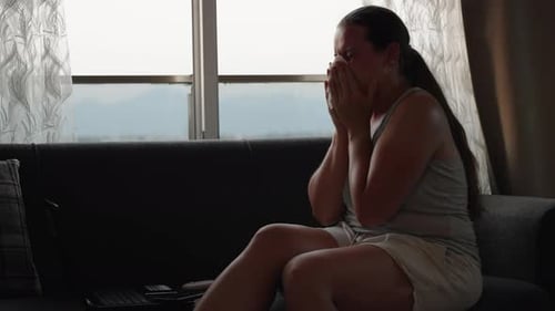 La jeune femme travaillait sur un ordinateur portable. Elle se mouche. Travail à distance. Assis sur le canapé. Une grippe
